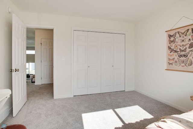 unfurnished bedroom featuring light carpet and a closet