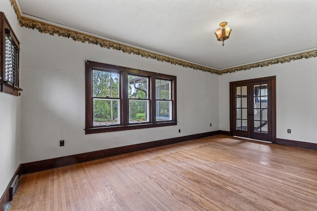 spare room with french doors, a textured ceiling, and light hardwood / wood-style flooring