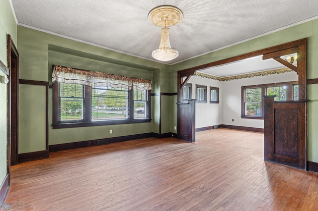 empty room with hardwood / wood-style flooring, ornamental molding, and a textured ceiling