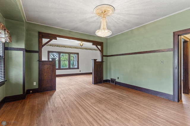 spare room with ornamental molding, light hardwood / wood-style floors, and a textured ceiling