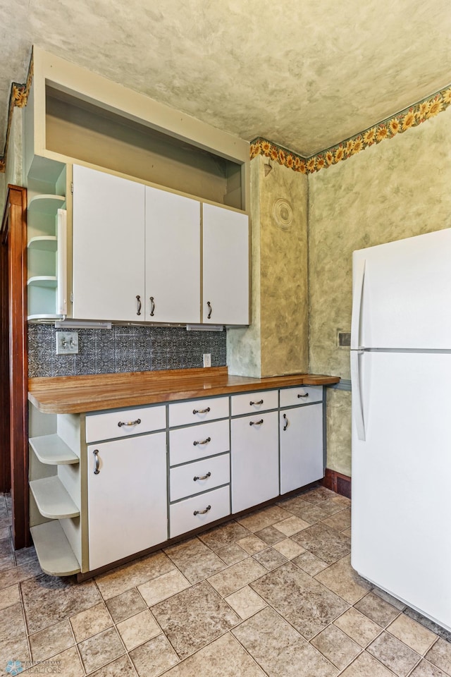 kitchen featuring white cabinets, backsplash, white refrigerator, and wood counters