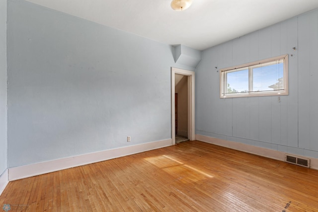 unfurnished room featuring wood walls and hardwood / wood-style floors