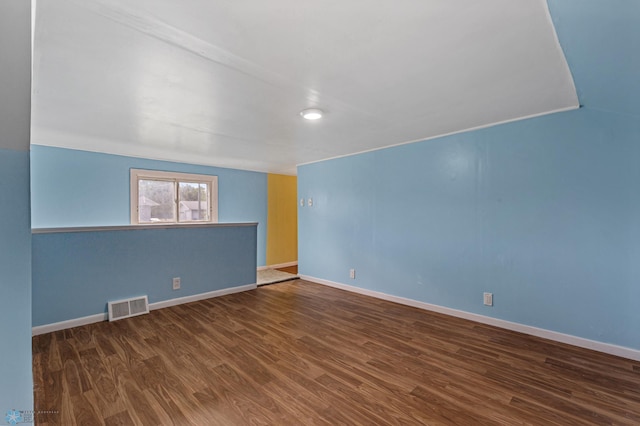 spare room featuring lofted ceiling and dark hardwood / wood-style flooring