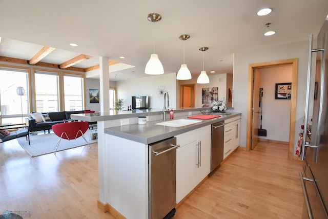 kitchen featuring pendant lighting, beamed ceiling, sink, white cabinetry, and kitchen peninsula