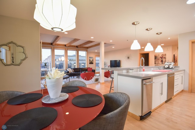 dining room with light hardwood / wood-style flooring, beamed ceiling, and sink