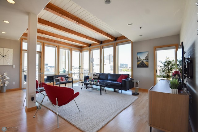 living room featuring beamed ceiling, wood ceiling, plenty of natural light, and light hardwood / wood-style floors