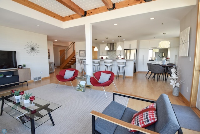 living room featuring light wood-type flooring, wood ceiling, and beamed ceiling