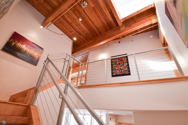 stairway featuring beam ceiling, a high ceiling, and wooden ceiling