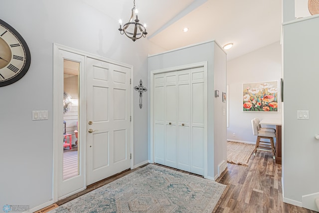 foyer with lofted ceiling, an inviting chandelier, and hardwood / wood-style flooring