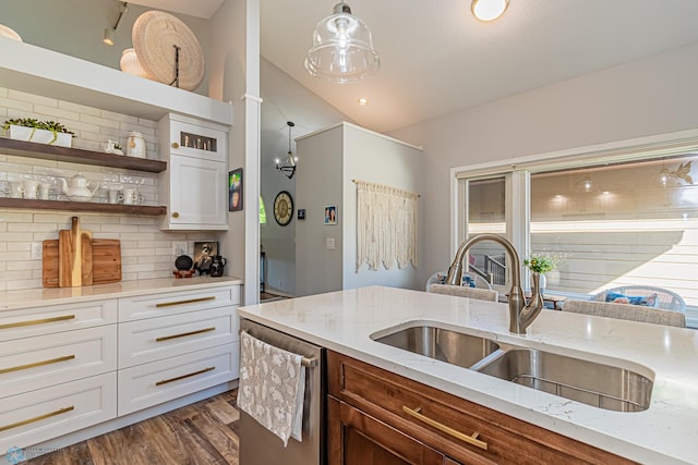 kitchen featuring backsplash, stainless steel dishwasher, hanging light fixtures, and white cabinetry