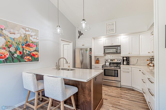 kitchen featuring white cabinetry, high vaulted ceiling, stainless steel appliances, a kitchen bar, and sink