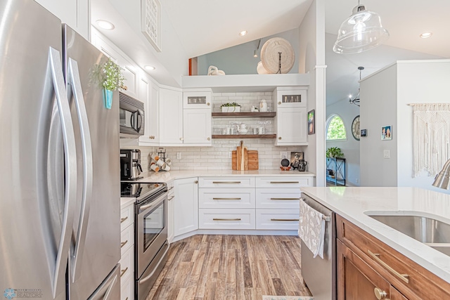 kitchen with light stone counters, decorative light fixtures, white cabinetry, appliances with stainless steel finishes, and decorative backsplash