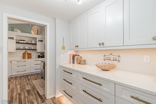 kitchen with light stone countertops, white cabinetry, a textured ceiling, and dark wood-type flooring