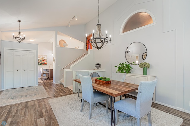 dining area featuring an inviting chandelier, hardwood / wood-style flooring, and high vaulted ceiling