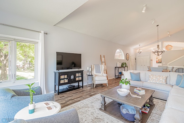 living room with wood-type flooring, lofted ceiling, and a notable chandelier