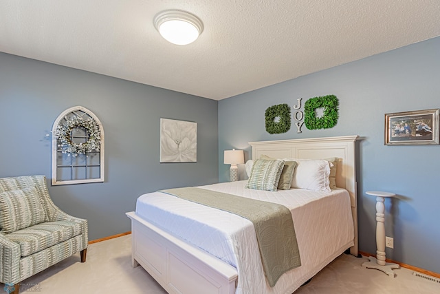 bedroom with a textured ceiling and light colored carpet