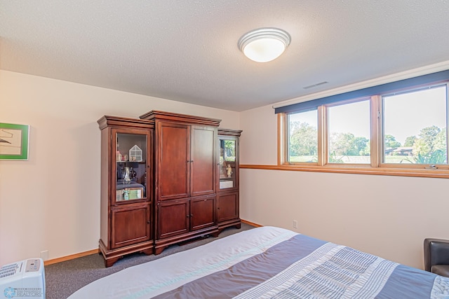 bedroom with a textured ceiling and dark carpet