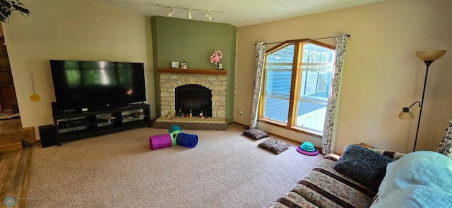 carpeted living room with a stone fireplace, a textured ceiling, and rail lighting