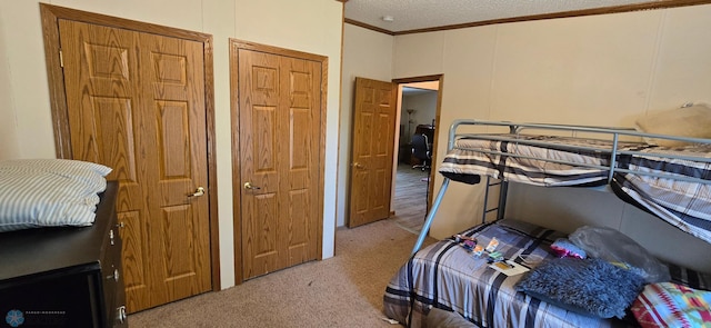 bedroom with a textured ceiling, carpet floors, and ornamental molding