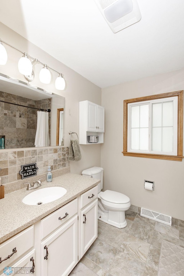 bathroom featuring vanity, backsplash, toilet, and curtained shower