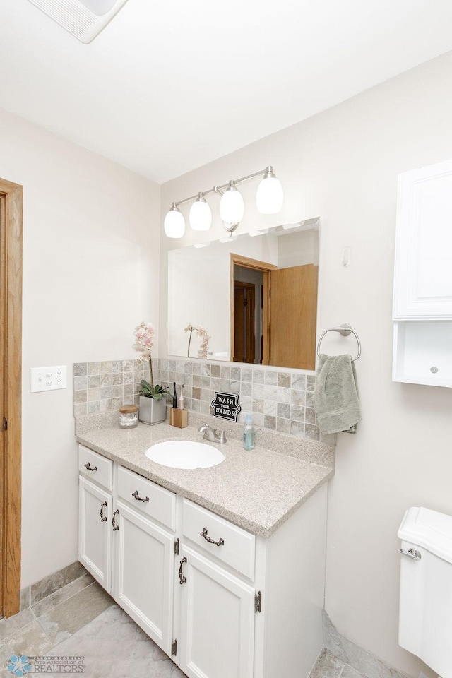 bathroom featuring vanity, toilet, and tasteful backsplash