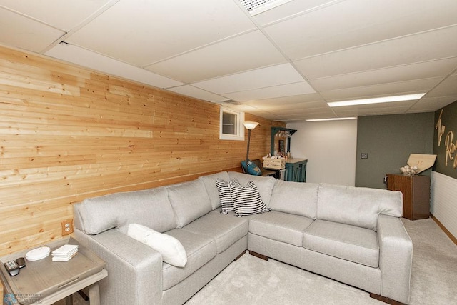 living room featuring wooden walls, carpet, and a paneled ceiling