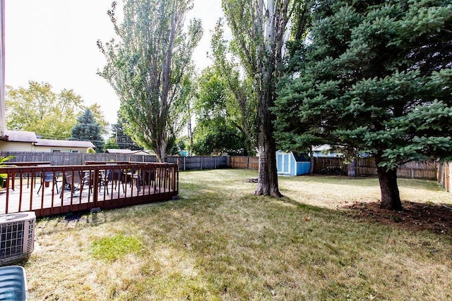 view of yard featuring a storage shed, a deck, and central AC unit