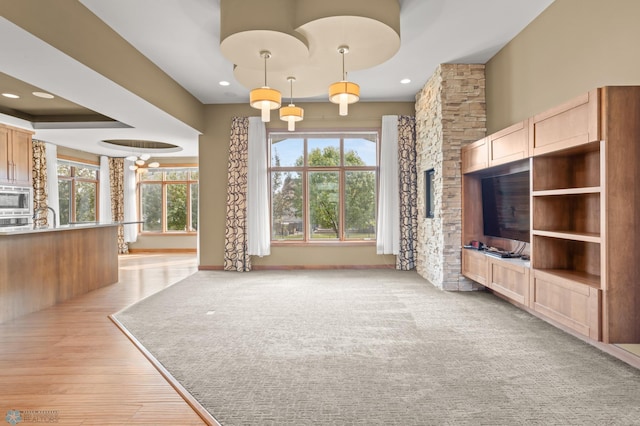 unfurnished living room featuring an inviting chandelier, light hardwood / wood-style floors, and a healthy amount of sunlight