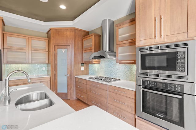 kitchen with light wood-type flooring, sink, wall chimney exhaust hood, stainless steel appliances, and backsplash