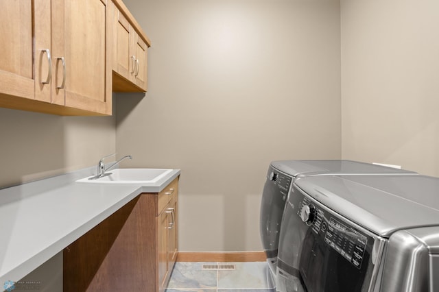 laundry area with cabinets, sink, light tile patterned floors, and washing machine and dryer