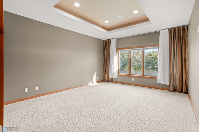 carpeted empty room featuring a tray ceiling