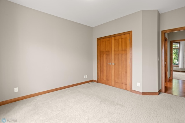 unfurnished bedroom with light carpet and a closet