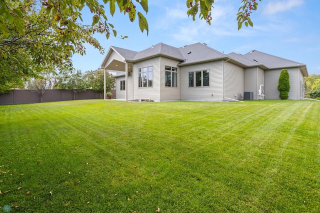 rear view of house featuring a yard and central air condition unit