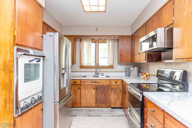 kitchen with stainless steel appliances, light tile patterned floors, and sink