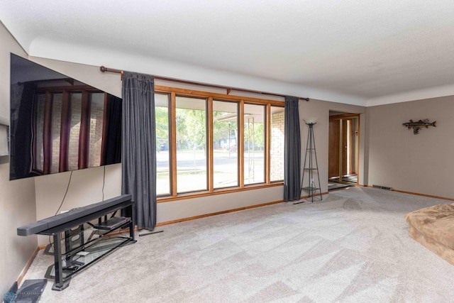 unfurnished living room featuring light carpet and a textured ceiling