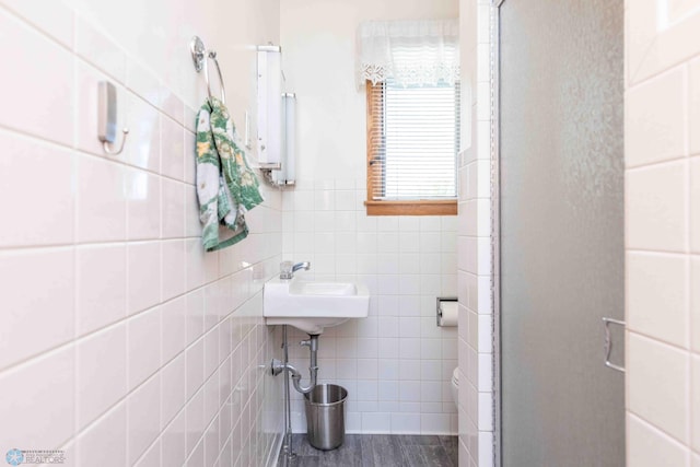 bathroom featuring tile walls, a shower with door, and sink