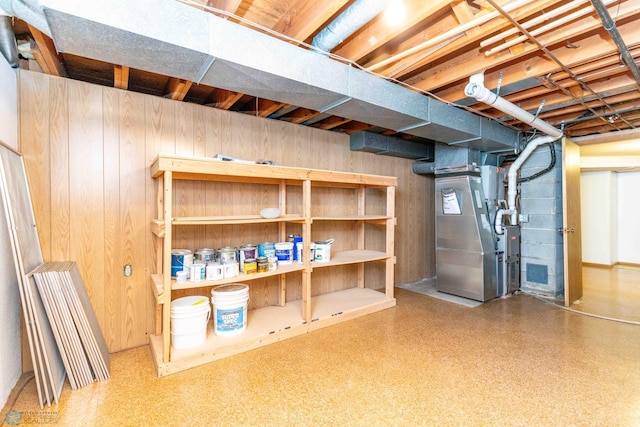 basement featuring heating unit and wood walls