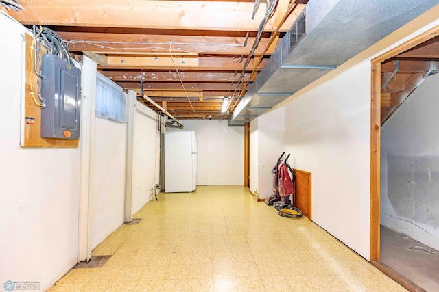 basement with white refrigerator and electric panel