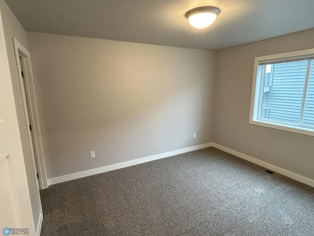 unfurnished room featuring dark colored carpet