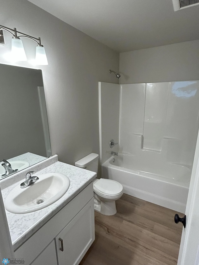 full bathroom featuring wood-type flooring, shower / tub combination, vanity, and toilet