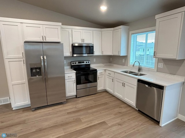 kitchen with lofted ceiling, sink, light hardwood / wood-style flooring, white cabinetry, and stainless steel appliances