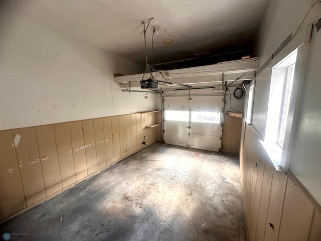 garage featuring a garage door opener and wooden walls