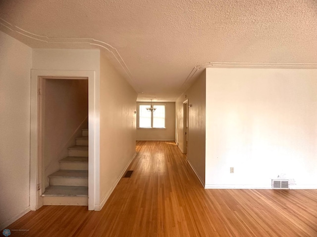 corridor with a textured ceiling and wood-type flooring