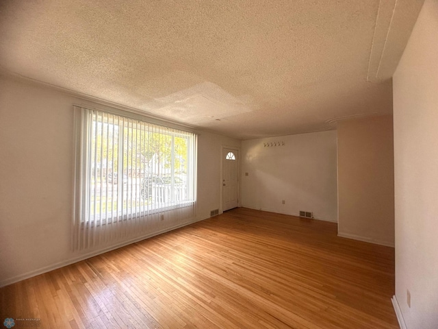 empty room featuring a textured ceiling and light hardwood / wood-style floors