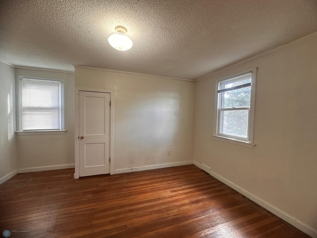 empty room with a textured ceiling, ornamental molding, and dark hardwood / wood-style flooring