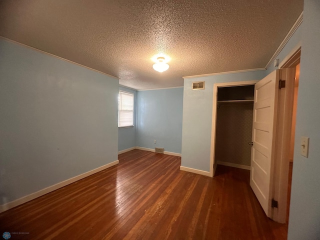 unfurnished bedroom featuring ornamental molding, a textured ceiling, a closet, and dark hardwood / wood-style flooring