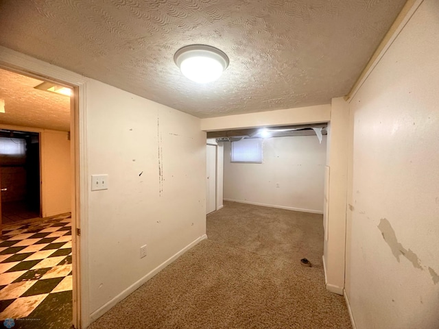 hallway with dark carpet and a textured ceiling