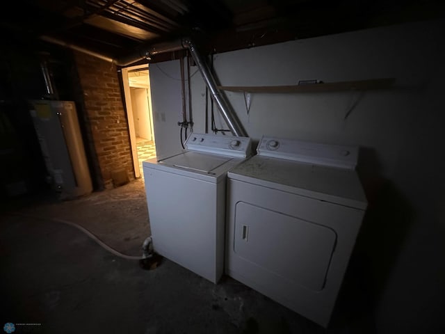 laundry room featuring brick wall, water heater, and washing machine and dryer