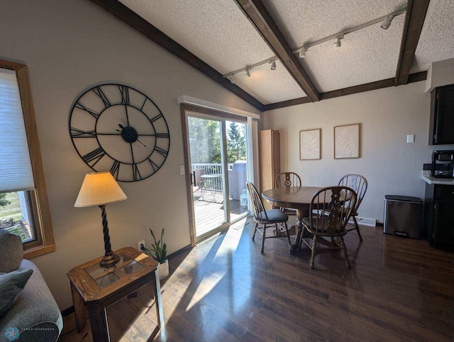 dining room featuring lofted ceiling with beams, a textured ceiling, track lighting, and dark hardwood / wood-style floors