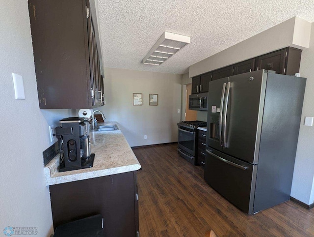 kitchen with sink, dark brown cabinets, a textured ceiling, stainless steel appliances, and dark hardwood / wood-style flooring